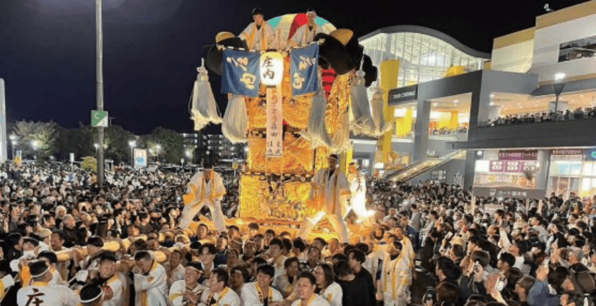 夜の会場で大勢の来場者に囲まれた豪華な山車の巡行風景