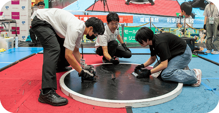 円形ステージで高校生の参加者がロボット相撲競技に取り組むイベントの様子
